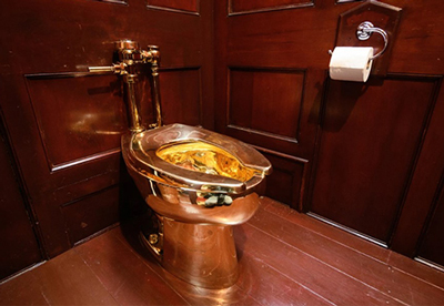a solid gold toilet in a dark wood paneled bathroom