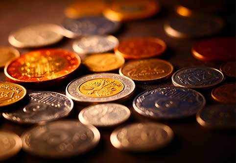 a pile on collectible coins in various denominations on a dark background